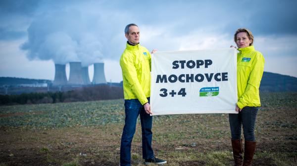 Zwei Aktivist:innen stehen vor dem AKW Mochovce mit "Stopp Mochocve Banner"