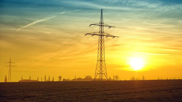 Strommasten in einem Feld bei Sonnenuntergang