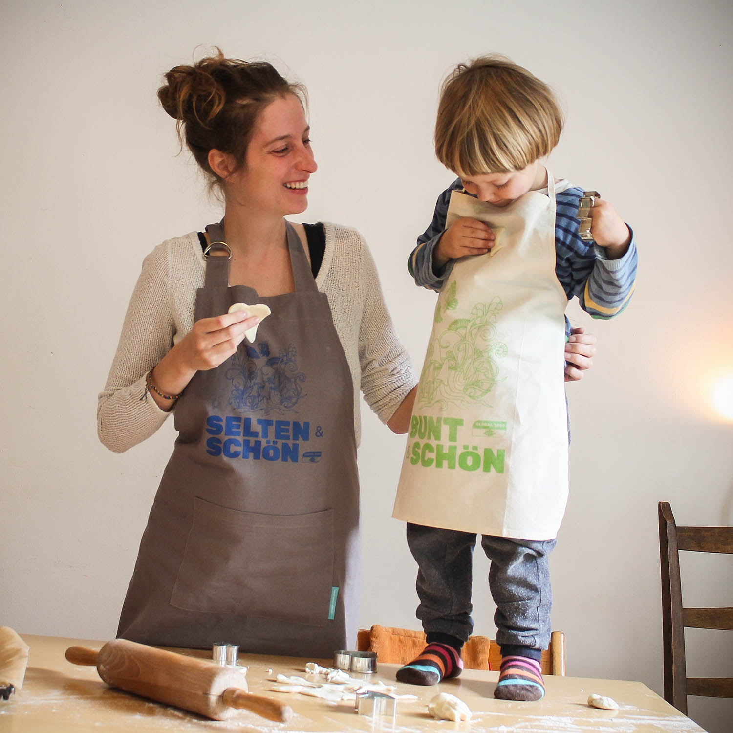 "Selten & Schön" Schürze von GLOBAL 2000 Mama mit Kind beim Kekse backen mit der "Selten & Schön" Schürze von GLOBAL 2000