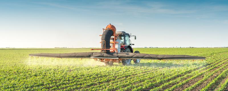 Traktor versprüht Pestizide über Sojafeld