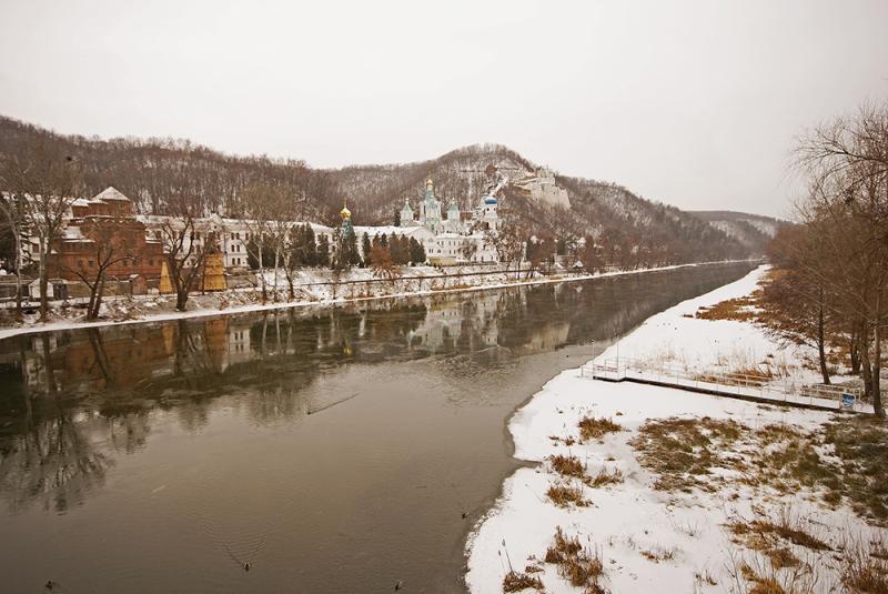 Fluss in Svyatogorsk mit Kloster im Hintergrund, dahinter Gebirge.