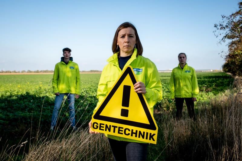 Brigitte Reisenberger, Gentechniksprecherin von GLOABAL 2000 hält  "Achtung Gentechnik"-Schild. Hinter ihr stehen zwei Aktivist:innen.
