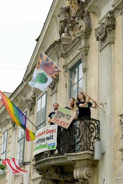 Anna Leitner hisst eine Fahne zum Welterschöpfungstag am Volkskundemuseum in Wien