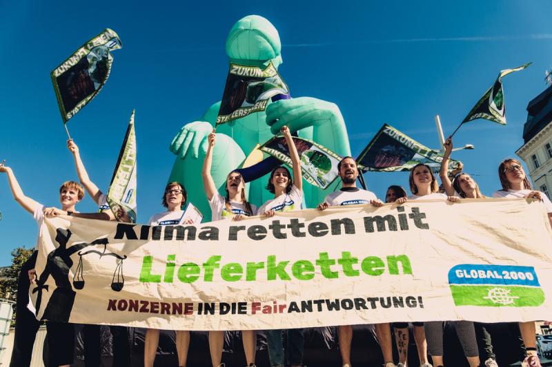 Aktivist:innen mit großem Banner "Klima retten mit Lieferketten" vor der Justizia Statue