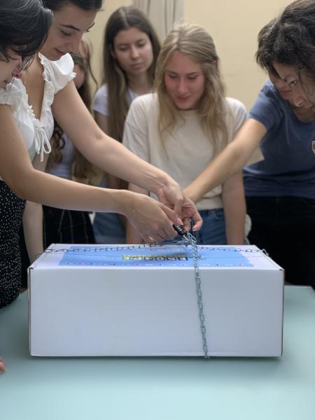 Jugendliche stehen um eine verschlossene Box und versuchen sie zu öffnen