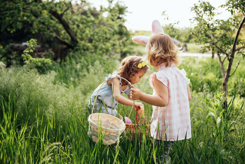 Zwei Mädchen auf der Suche nach Ostereiern im hohen Gras