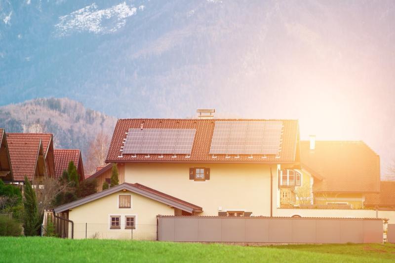 Einfamilienhaus im Sonnenuntergang. Auf den Dächern sind Solarmodule installiert.