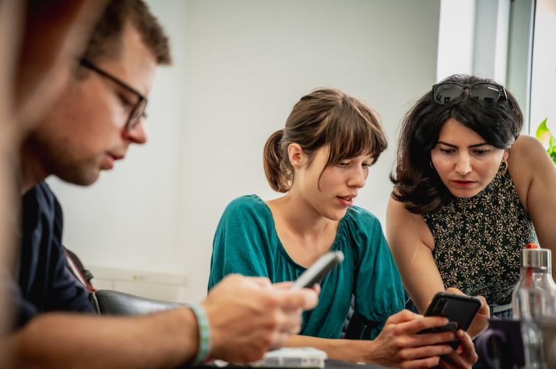 Mehrere Personen schauen auf ihre Handys und diskutieren