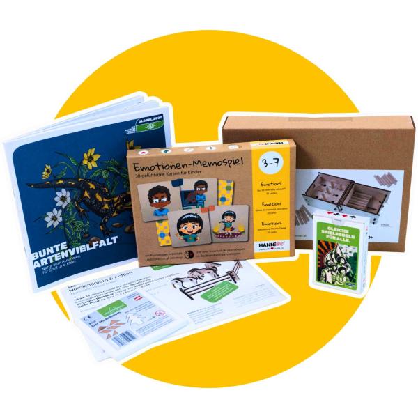 Bunte Vielfalt an Lernmaterialien und Spielen vor gelbem Hintergrund, darunter ein Buch mit dem Titel 'Bunte Artenvielfalt', ein Emotionen-Memospiel für Kinder, ein Kartenspiel 'Gleicher Spielen für Alle' und ein Holzspiel mit Anleitung.