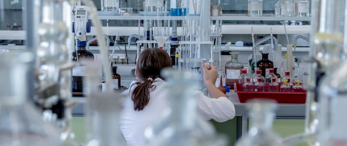Frau hantiert mit Chemikalien im Labor 