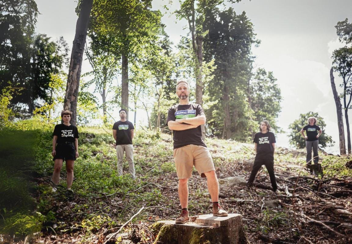 GLOBAL 2000 Mitarbeiter:innen stehen in einem abgeholzten Wald