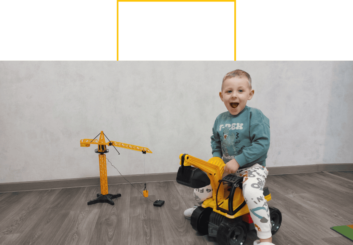 Junge sitzt auf Spielzeug-Bagger und lacht