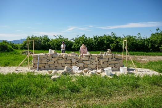 Personen beim Bauen einer freistehenden Trockensteinmauer