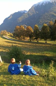 Oksanas Söhne sitzen in der Wiese und schauen in die Berge