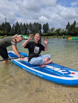 Mädchen sitzt auf Surfboard im Wasser