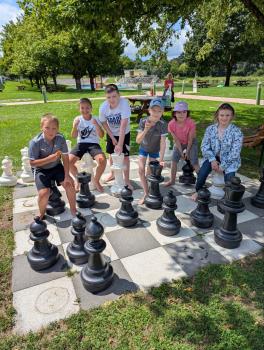 Kinder spielen mit großem Schachbrett im Park