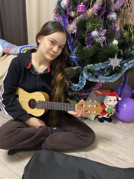 Mädchen mit Gitarre vor Weihnachtsbaum