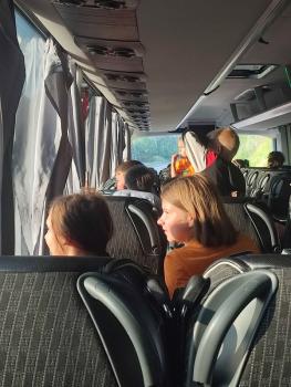 Mehrere Kinder sitzen in einem Bus und blicken aus den Fenstern, Sonnenlicht fällt auf ihre Gesichter