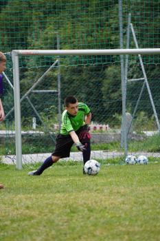 Torwart in grünem Trikot fängt einen Fußball vor dem Tor auf einem Fußballfeld