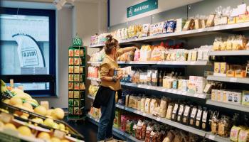 Frau sortiert Waren in Regale im MILA MItmach-Supermarkt