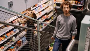 Mann geht Stiegen hinauf und trägt Einkaufskorb im MILA Mitmach-Supermarkt