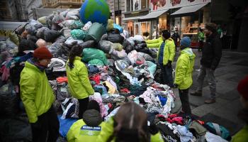 Aktivist:innen von GLOBAL 2000 mit Kleidungsberg und Erdball auf Straße