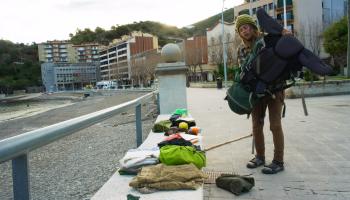 Weltwanderer am Strand räumt Rucksack aus