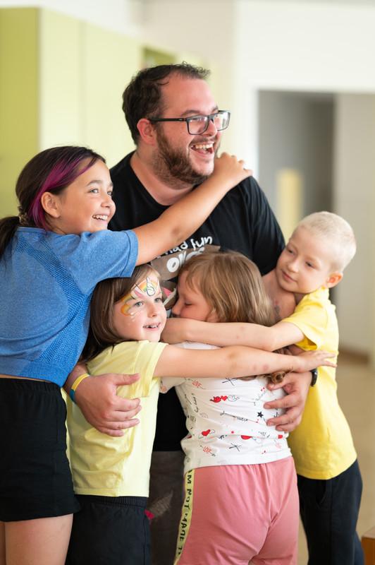 Vier Kinder umarmen sehr herzlich einen Betreuer 