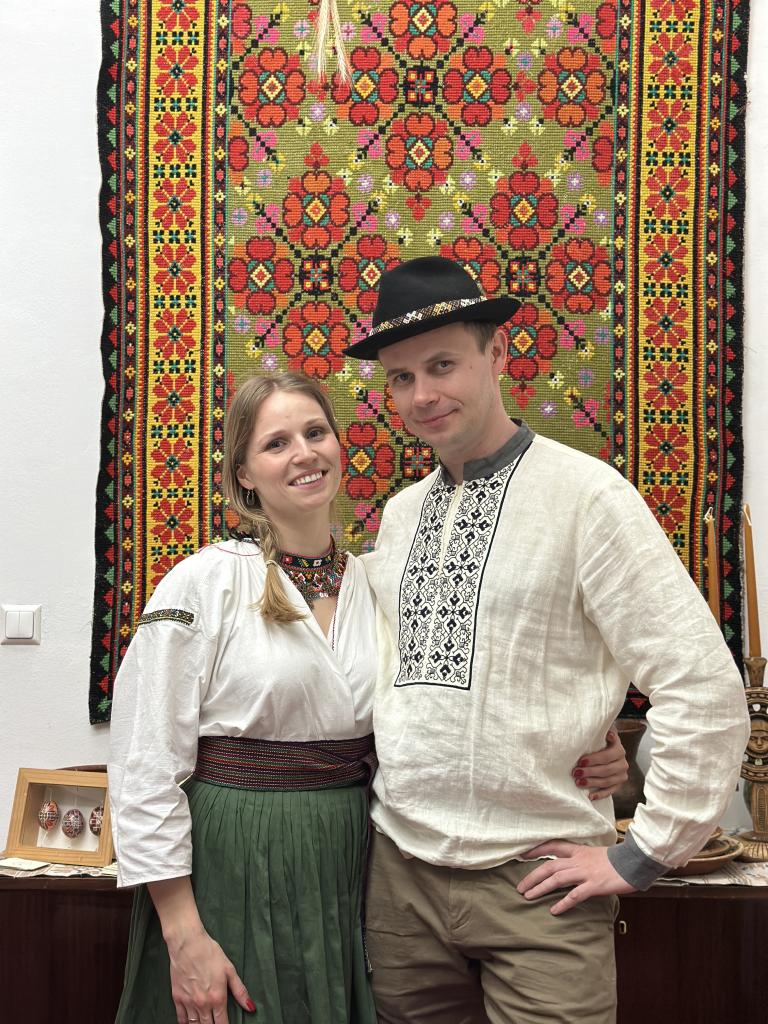 Ukrainisches Paar vor Wandteppich in Tracht