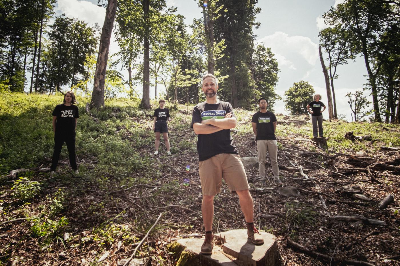 GLOBAL 2000 Mitarbeiter:innen stehen in einem abgeholzten Wald
