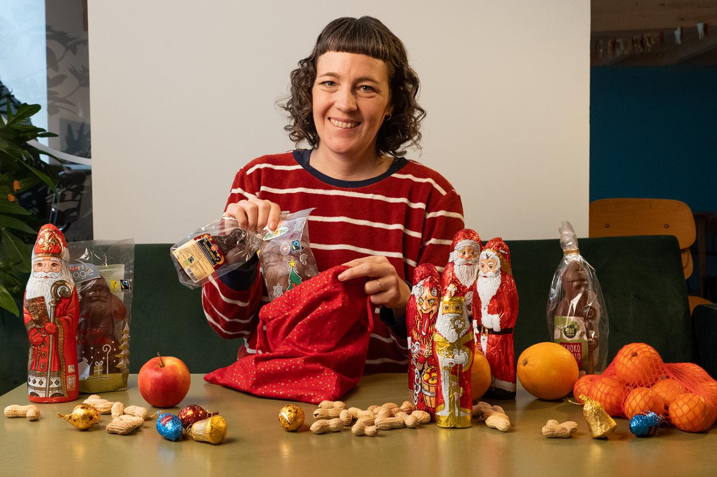 Frau im rot-weiß-gestreiften Shirt steckt Schoko-Nikoläuse in einen Nikolo-Sack.