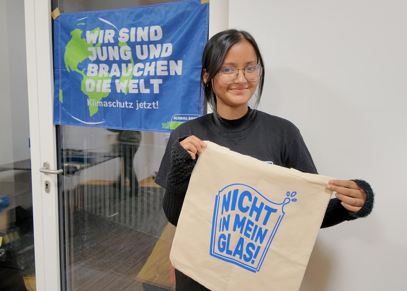 Fariha mit einem Siebdruck-Beutel vor einem Banner 