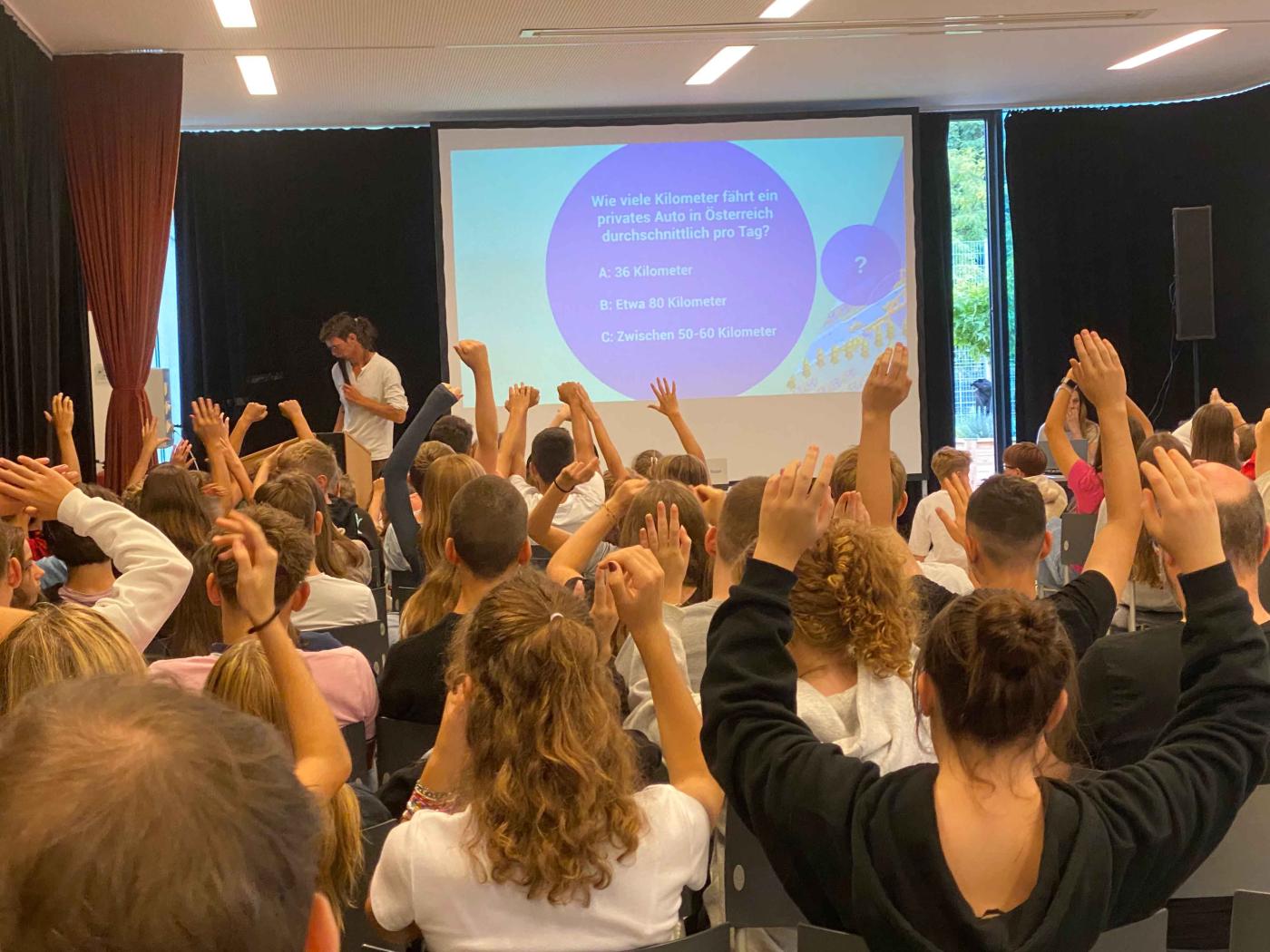 Schüler:innen zeigen auf in Multivisions-Vortrag