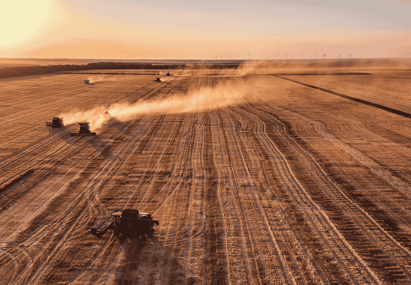 Mehrere landwirtschaftliche Geräte fahren über ein Feld über rötliche Erde