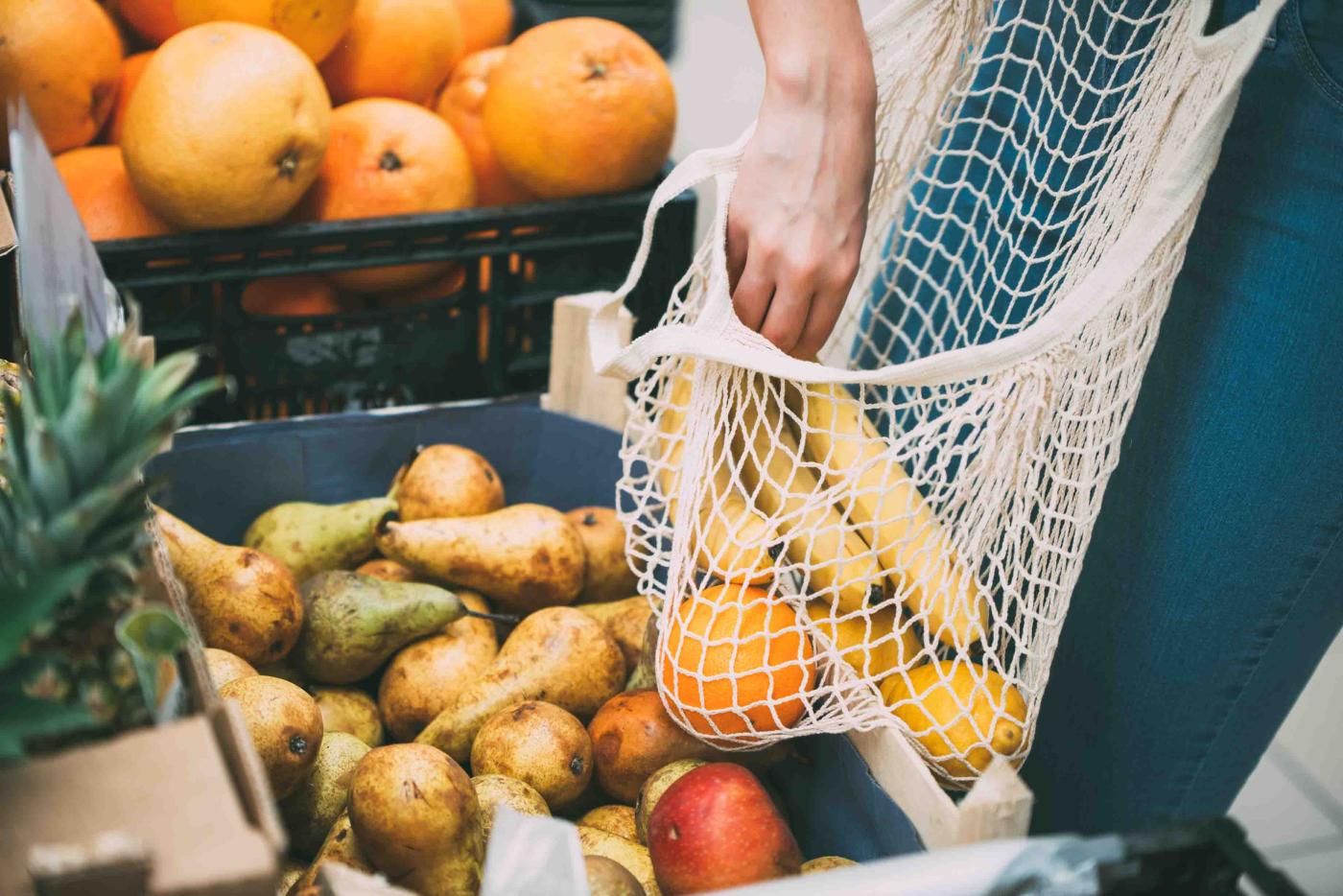 Einkaufsnetz wird im Supermarkt mit Gemüse gefüllt