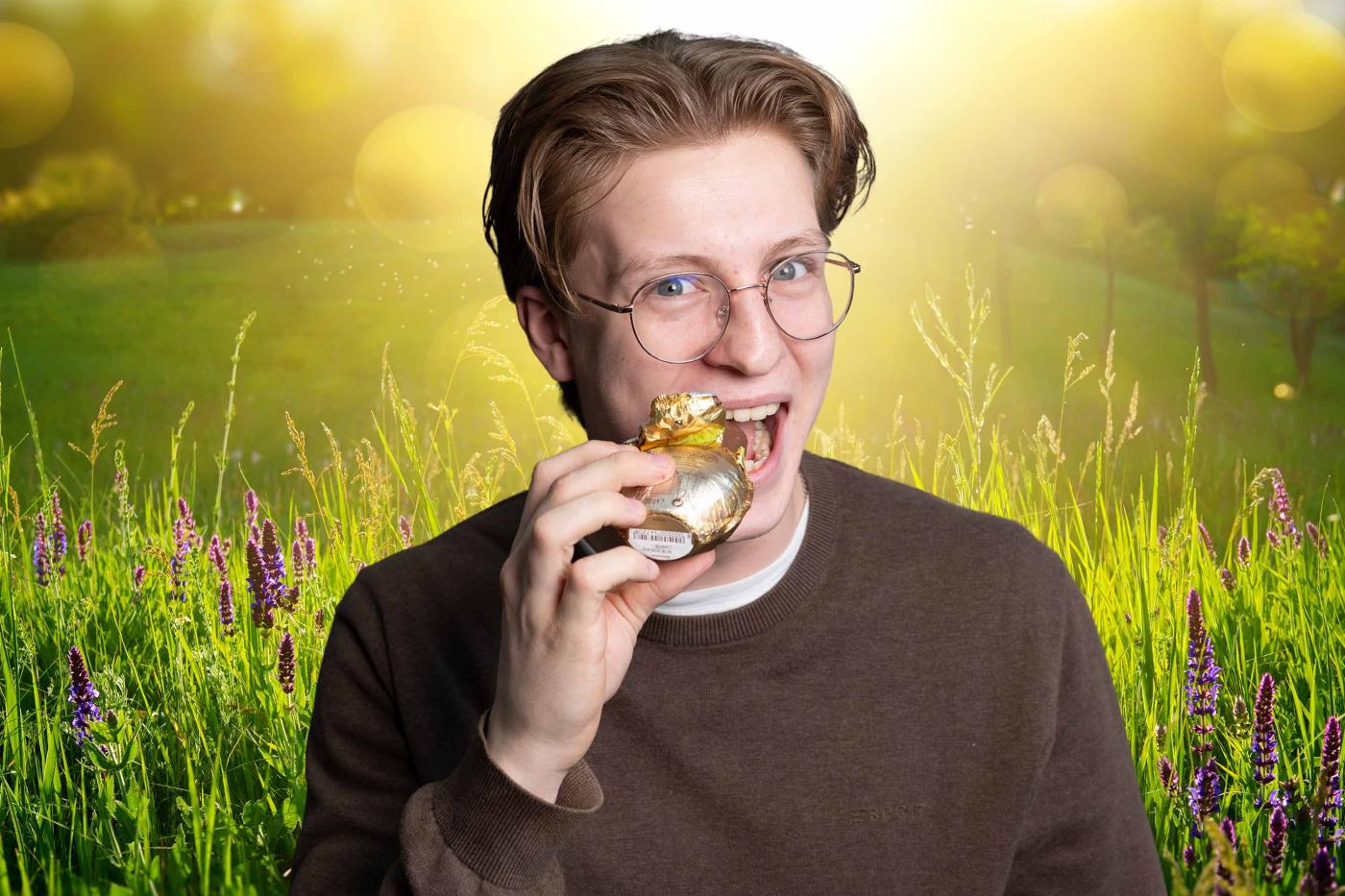 Junge beißt bei Schoko-Osterhasen ab, Fotomontage vor frühlingshaftem Hintergrund