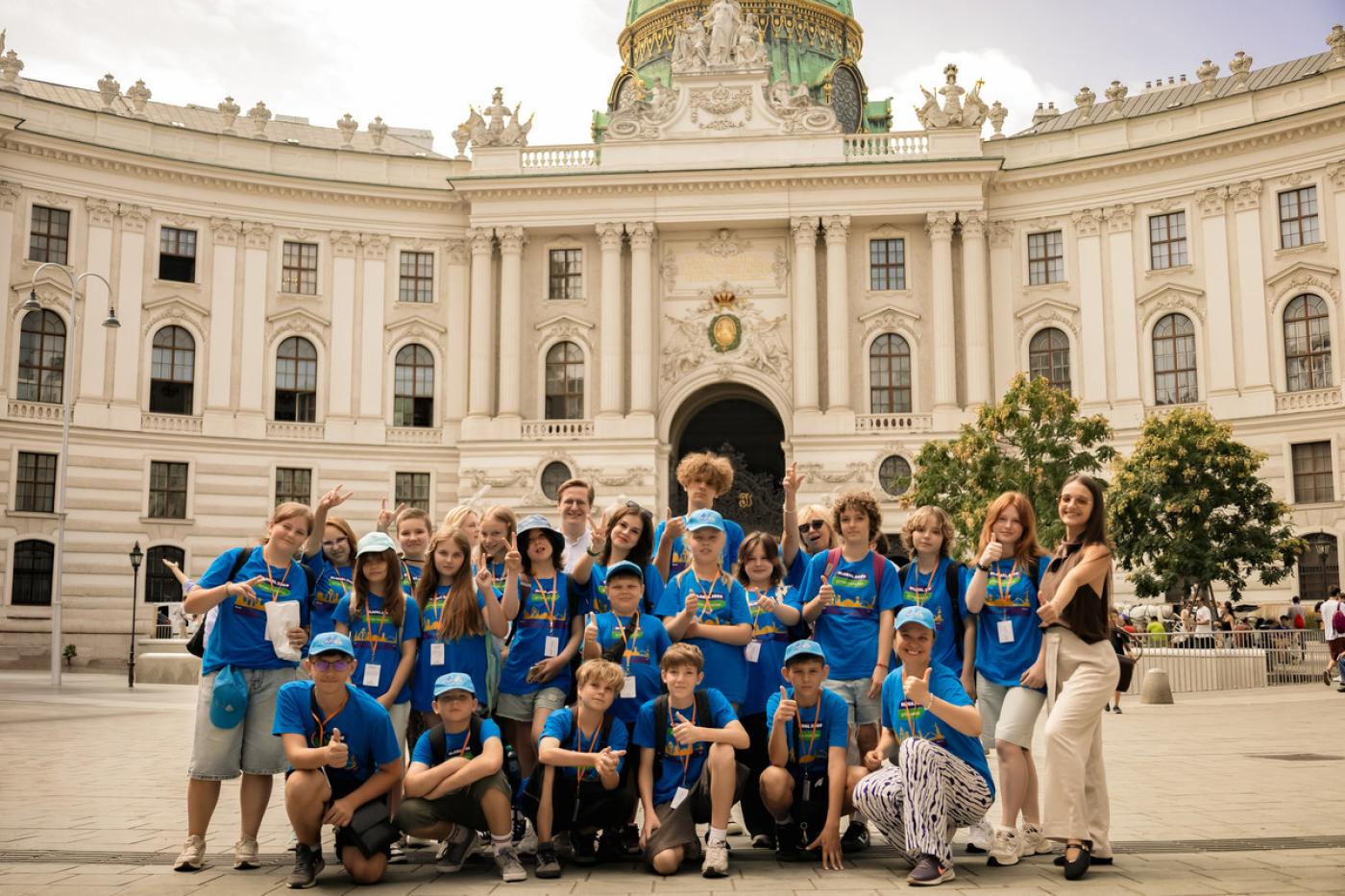 Gruppe von Kindern und Jugendlichen in blauen T-Shirts posiert vor der Hofburg in Wien