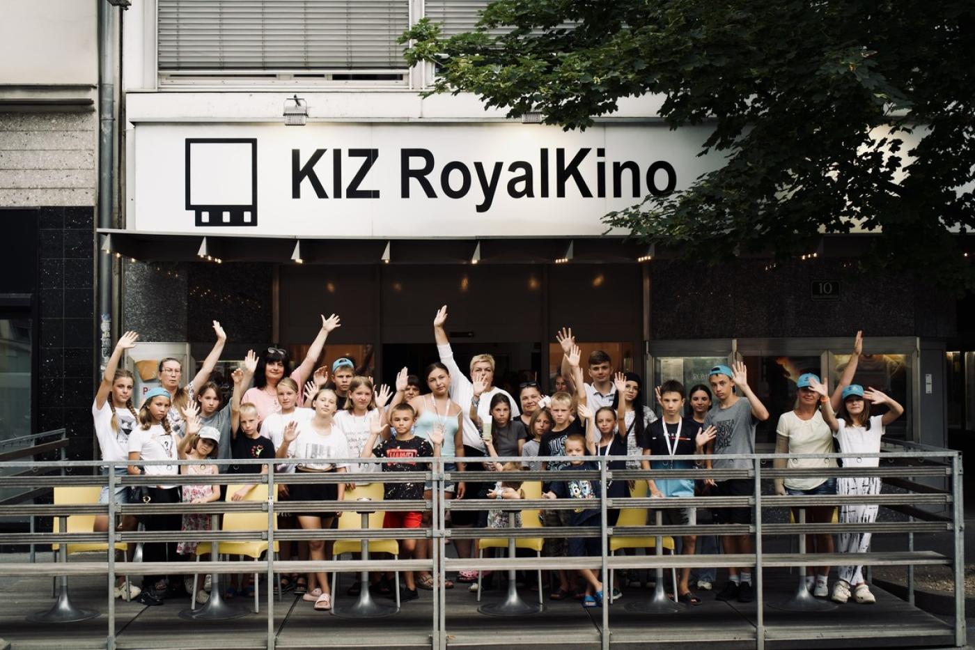 Gruppe von Kindern und Jugendlichen vor dem Kino KIZ RoyalKino, viele winken in die Kamera