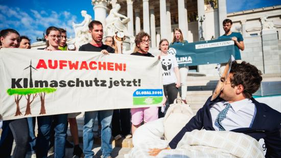 Aktivist:innen inszenieren eine Aktion vor dem Parlament um auf den Klimaschutz aufmerksam zu machen