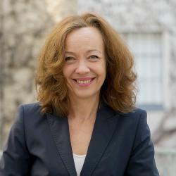 Astrid Stelmann, mit dunkel blauen Blazer und schulterlangen Haaren lächelt in die Kamera