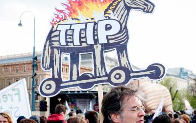 Ein Mann mit einem Schild auf den das trojanischen TTIP-Pferd zu sehen ist, auf der TTIP-Demo in Wien 2015