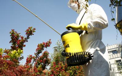 Mann in Schutzanzug versprüht Pestizide