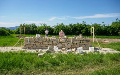 Personen beim Bauen einer freistehenden Trockensteinmauer