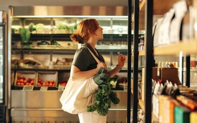 Frau steht vor Supermarktregal und sucht nach dem richtigen Produkt