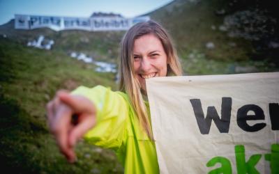 Klimaaktivistin lacht und zeigt mit dem Finger in die Kamera