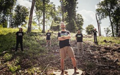 GLOBAL 2000 Mitarbeiter:innen stehen in einem abgeholzten Wald