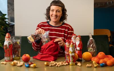 Frau im rot-weiß-gestreiften Shirt steckt Schoko-Nikoläuse in einen Nikolo-Sack.