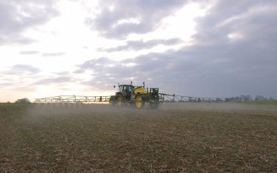 Traktor spritzt Pestizide auf einem Feld. 
