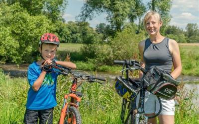 Eine blonde Frau und ein kleiner Junge schieben ihre Fahrräder durch die Natur