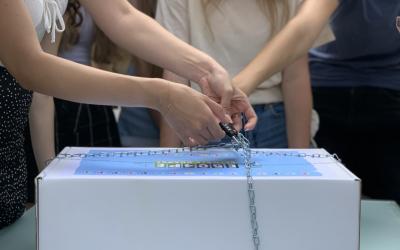 Jugendliche stehen um eine verschlossene Box und versuchen sie zu öffnen